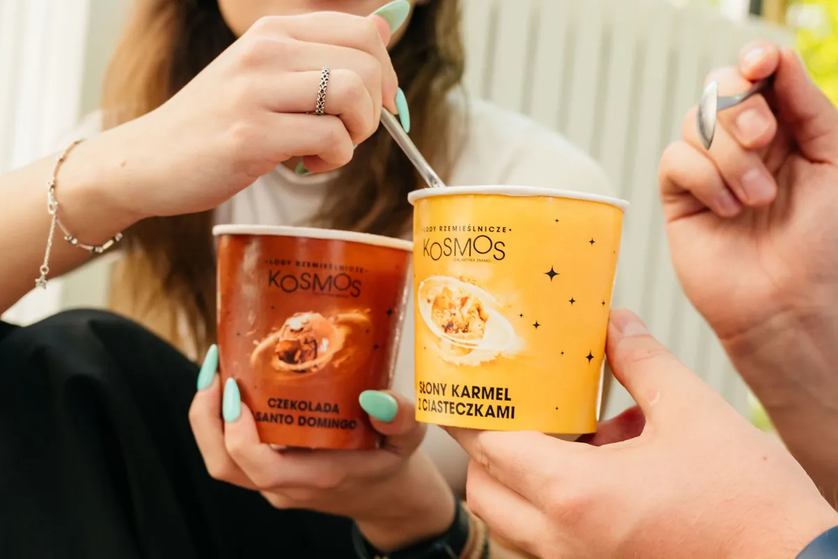 Lody KOSMOS Czekolada z Santo Domingo i Słony karmel w kubkach w dłoniach klientów